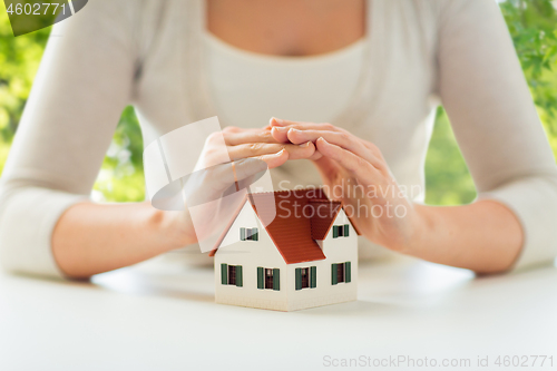 Image of close up of woman protecting house model by hands