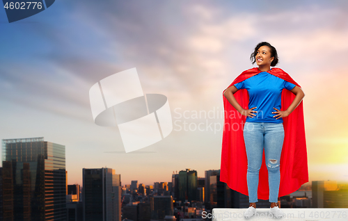 Image of happy african american woman in superhero red cape