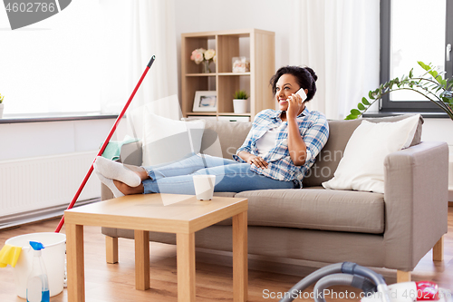 Image of woman calling on smartphone after home cleaning