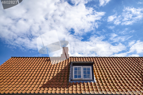 Image of Tiled red roof with a rooftop window
