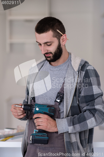 Image of the worker holding a hand drilling machine