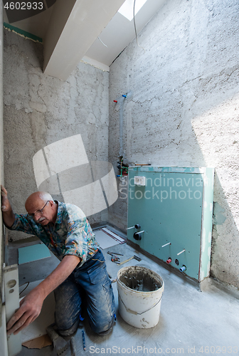 Image of worker using level tool while installing big ceramic tiles