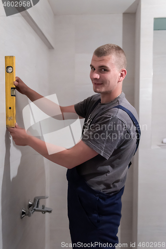 Image of professional plumber using bubble level in a bathroom