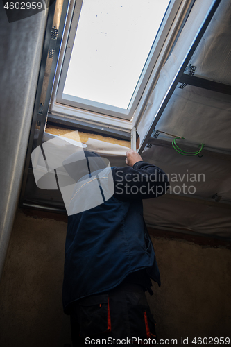 Image of roofer man installing thermal insulation layer