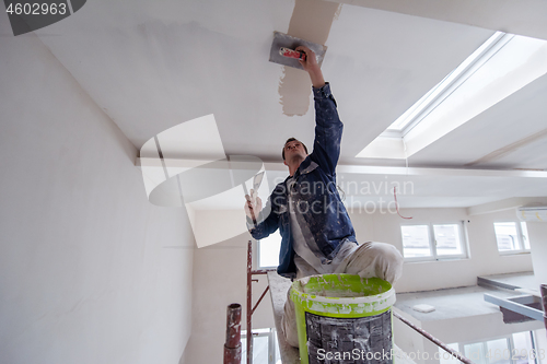 Image of construction worker plastering on gypsum ceiling