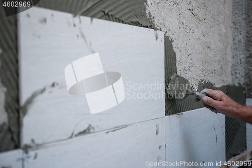 Image of worker installing big ceramic tiles