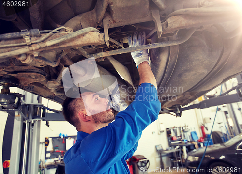 Image of mechanic man with flashlight repairing car at shop