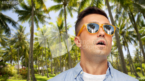 Image of surprised man in sunglasses over tropical beach