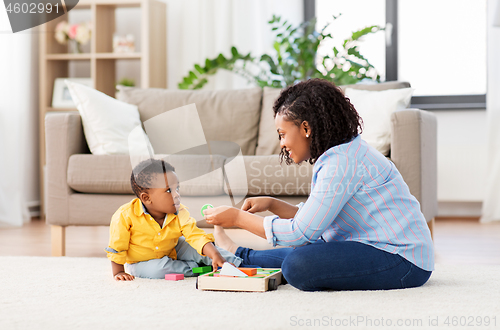 Image of mother and baby playing with toy blocks at home