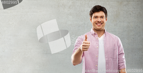 Image of man showing thumbs up over grey concrete wall