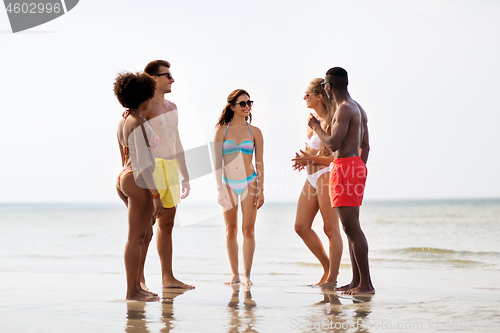 Image of happy friends hugging on summer beach