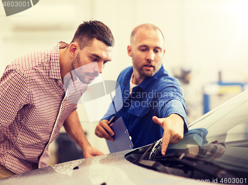 Image of auto mechanic with clipboard and man at car shop