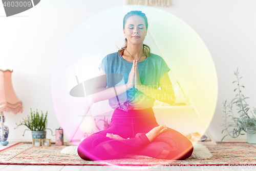 Image of woman meditating in lotus pose at yoga studio