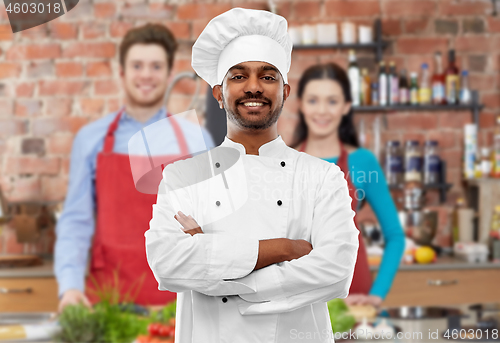 Image of happy male indian chef in toque at cooking class