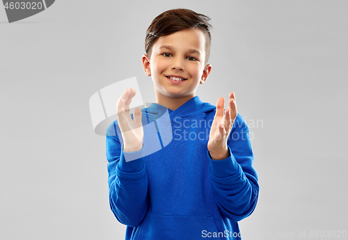 Image of portrait of smiling boy in blue hoodie applauding