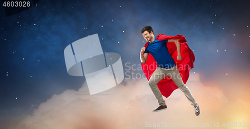 Image of man in red superhero cape flying over night sky