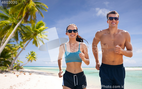 Image of couple in sports clothes running along on beach