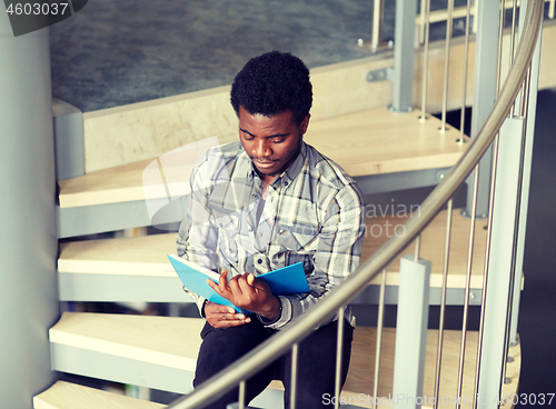 Image of african student boy or man reading book on stairs