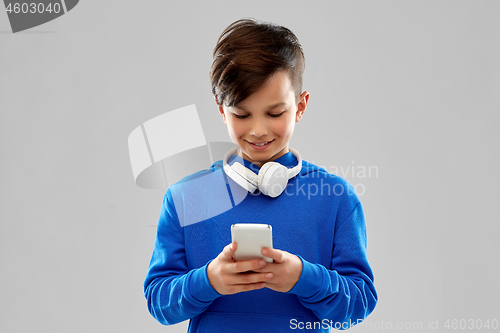 Image of smiling boy in blue hoodie using smartphone