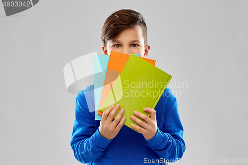 Image of shy student boy hiding behind books