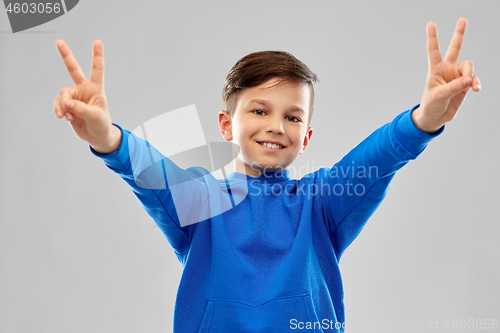 Image of smiling boy in blue hoodie showing peace gesture