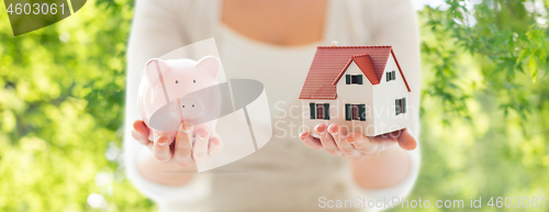 Image of close up of woman with house model and piggy bank