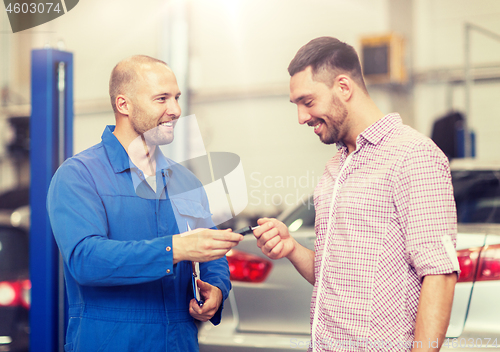 Image of auto mechanic giving key to man at car shop