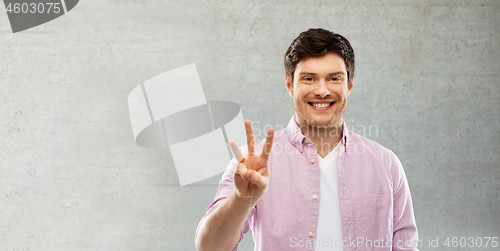 Image of man showing three fingers over gray concrete wall