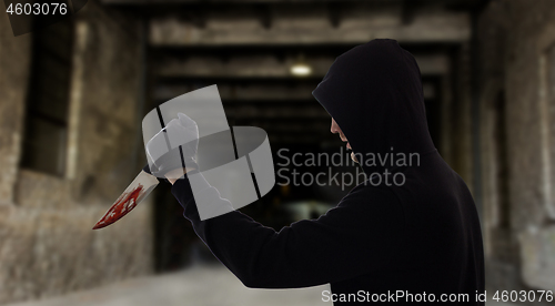 Image of criminal with bloody knife over dark gateway