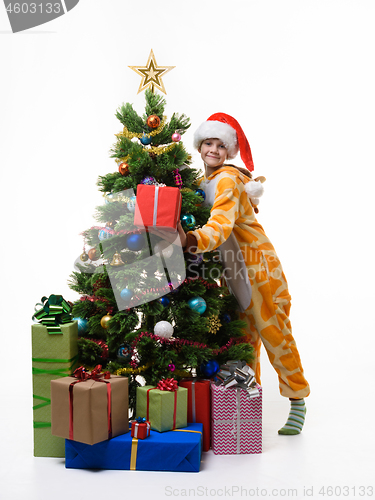 Image of Girl with a gift hugs Christmas tree