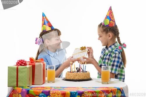 Image of A girl gives a gift to her friend at the holiday table