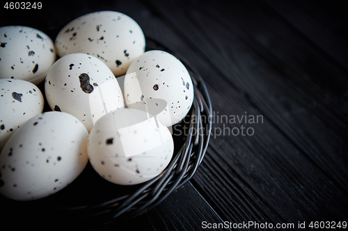 Image of Whole Chicken eggs in a nest on a black rustic wooden background. Easter symbols