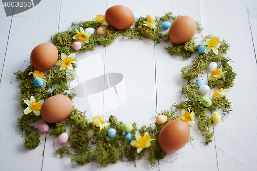 Image of Colorful decorative Easter eggs wreath on white wooden table background