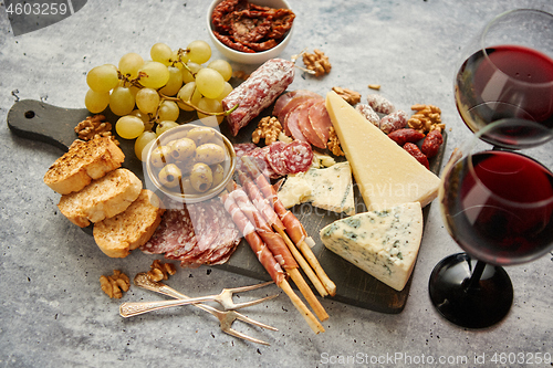 Image of Cold snacks board with meats, grapes, wine, various kinds of cheese