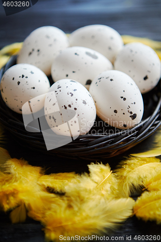 Image of Whole Chicken eggs in a nest on a black rustic wooden background. Easter symbols