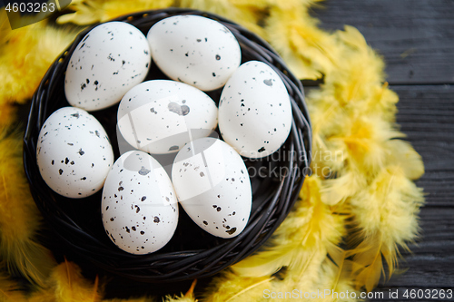 Image of Whole Chicken eggs in a nest on a black rustic wooden background. Easter symbols