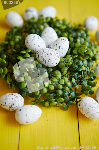 Image of Green decorative Easter quail eggs wreath on yellow wooden table