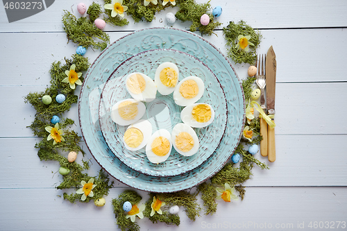 Image of Easter table setting with flowers and eggs. Decorative plates with boiled eggs