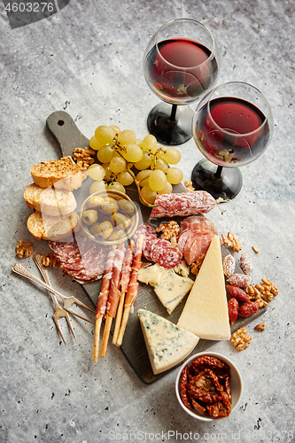 Image of Cold snacks board with meats, grapes, wine, various kinds of che