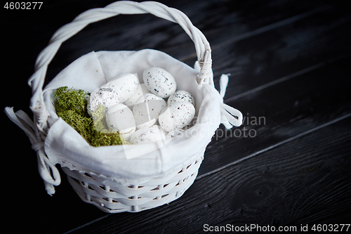 Image of Quail eggs in a nest on a black rustic wooden background. Easter symbols