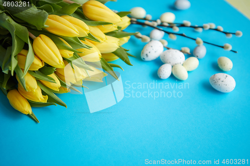 Image of Holiday contept decoration with easter eggs and yellow tulips over blue