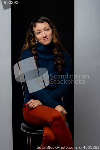 Image of Funny cute girl sits on a chair on a black and gray background