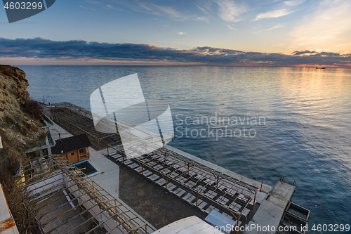 Image of Sunset view on an empty sunlounge beach on a rocky sea shore