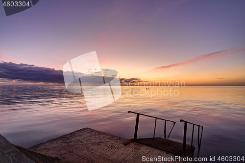 Image of view of the evening sea from the pier, a ladder descends into the sea