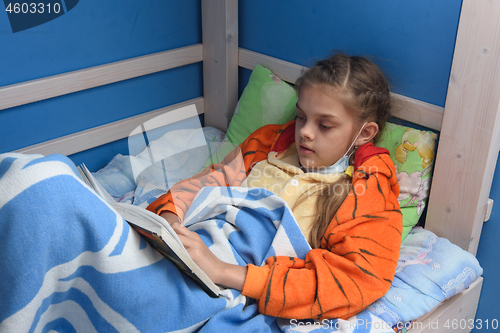 Image of Sick girl reads a book lying in bed in bed