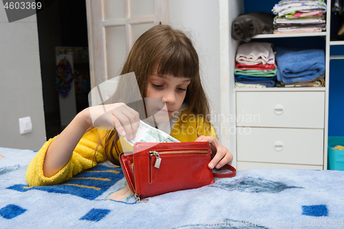 Image of The girl opened her mothers wallet and pulls out a thousand-ruble note