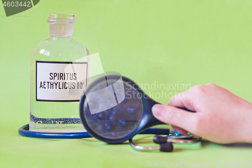 Image of Ethanol in a bottle on the table with of microscope virus close up, stethoscope and loupe with fingers. Coronavirus concept