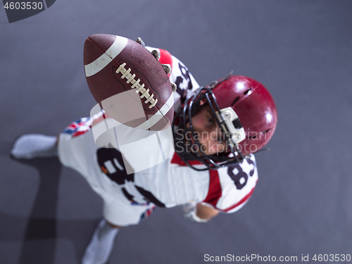 Image of american football player showing football to camera