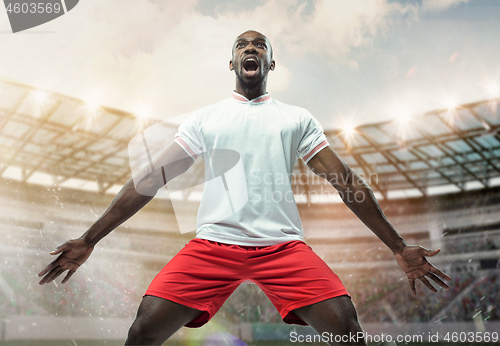 Image of The football player in motion on the field of stadium