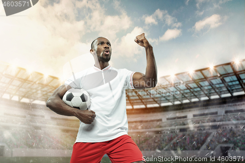 Image of The football player in motion on the field of stadium